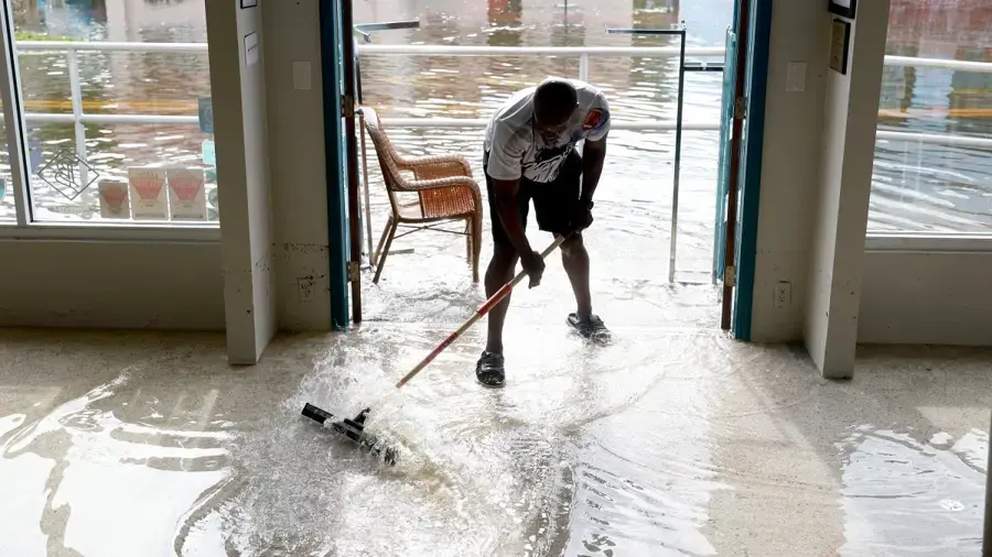 Homeowner pushing flood water out through open doors of a Florida home