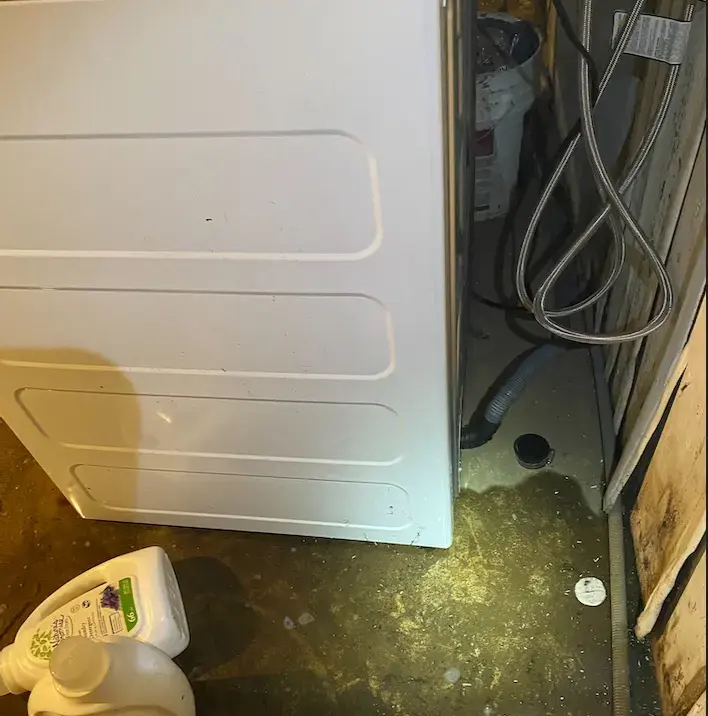 Water pooled on the floor beside a washing machine after a hose leak