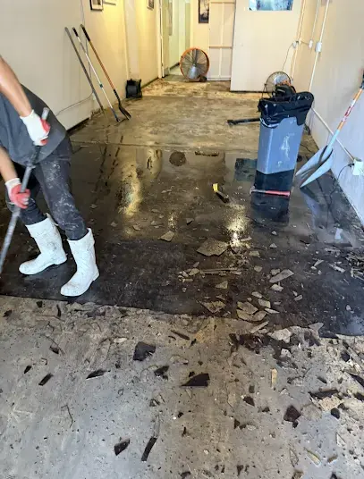 Crew extracting muddy water and lifting soaked flooring off a North Port slab