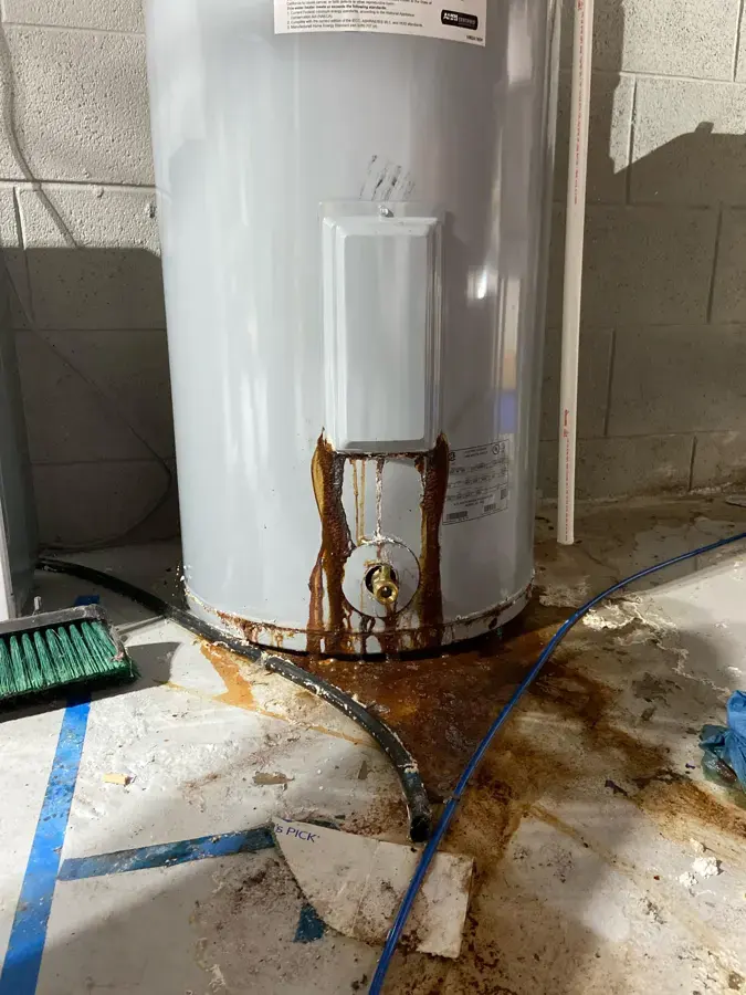 Leaking garage water heater with rusty water spread across the floor