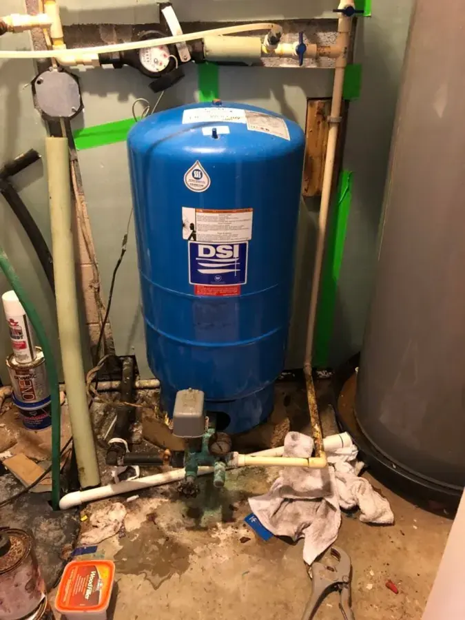 Well pressure tank with towels on a wet floor after a fitting leak